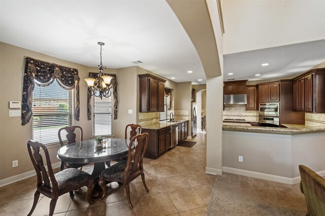 13803 Oak Fair Bnd, Cypress, TX 77429 - dining area featuring arched walkways, a chandelier, light tile patterned floors, recessed lighting, and baseboards