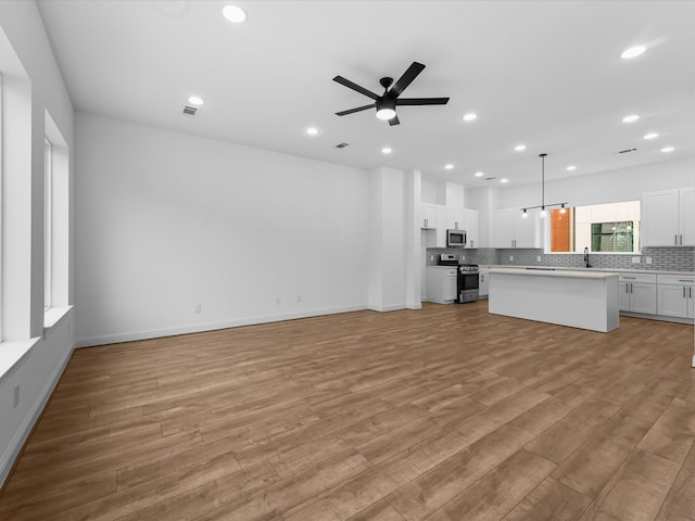 2318 Mcilhenny St, Houston, TX 77004 - unfurnished living room featuring light wood-style floors, recessed lighting, a ceiling fan, baseboards, and a sink