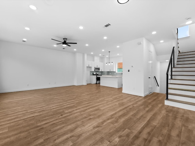 2318 Mcilhenny St, Houston, TX 77004 - unfurnished living room with recessed lighting, light wood finished floors, a ceiling fan, stairs, and healthy amount of natural light