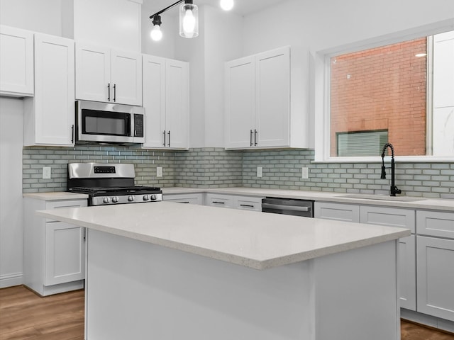 2318 Mcilhenny St, Houston, TX 77004 - kitchen with appliances with stainless steel finishes, a sink, a kitchen island, white cabinetry, and tasteful backsplash