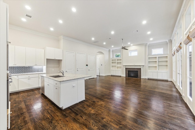 1701 Wrenwood Lks, Houston, TX 77043 - kitchen with a sink, crown molding, ceiling fan, a center island with sink, and a glass covered fireplace