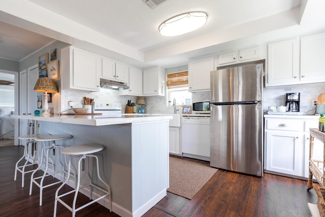 16627 Bermuda Way, Jamaica Beach, TX 77554 - kitchen with white appliances, under cabinet range hood, white cabinetry, and dark wood-style flooring