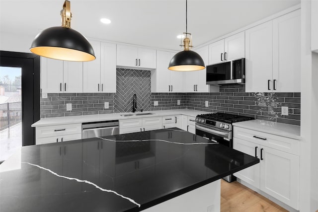 8707 Wind Side Dr, Houston, TX 77040 - kitchen featuring appliances with stainless steel finishes, a sink, backsplash, white cabinetry, and pendant lighting