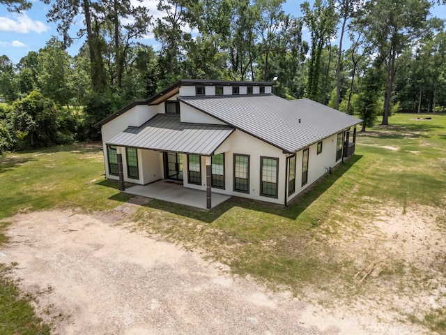 15086 Dewberry Ln, Conroe, TX 77302 - view of front of house with a standing seam roof, a patio area, metal roof, stucco siding, and a front lawn