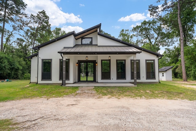 15086 Dewberry Ln, Conroe, TX 77302 - rear view of house featuring a standing seam roof, stucco siding, a yard, metal roof, and french doors