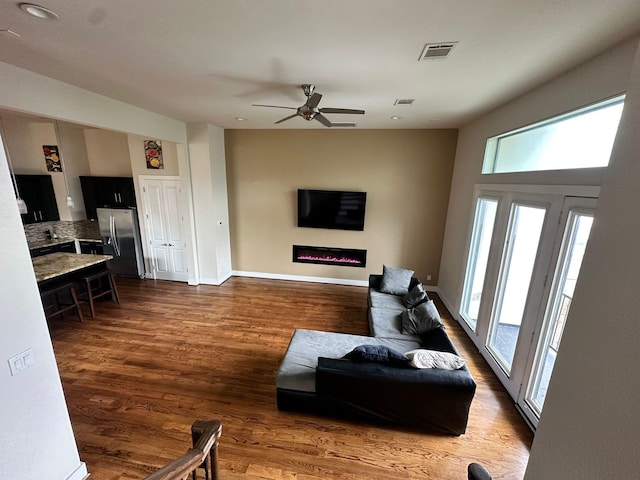 1613 Bonner St, Houston, TX 77007 - living area with dark wood-style flooring, ceiling fan, a glass covered fireplace, and baseboards