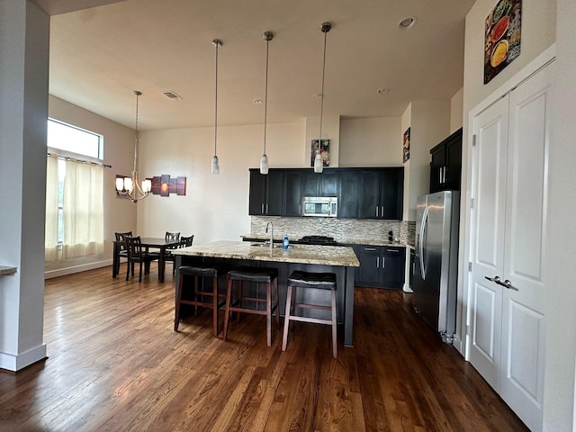 1613 Bonner St, Houston, TX 77007 - kitchen with appliances with stainless steel finishes, a kitchen breakfast bar, tasteful backsplash, a chandelier, and dark wood finished floors
