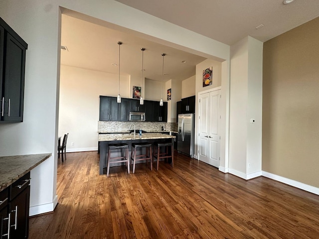 1613 Bonner St, Houston, TX 77007 - kitchen featuring appliances with stainless steel finishes, a breakfast bar area, dark wood-style flooring, decorative backsplash, and baseboards