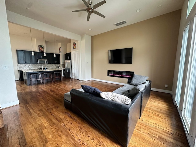1613 Bonner St, Houston, TX 77007 - living room featuring a ceiling fan, a glass covered fireplace, dark wood finished floors, and baseboards