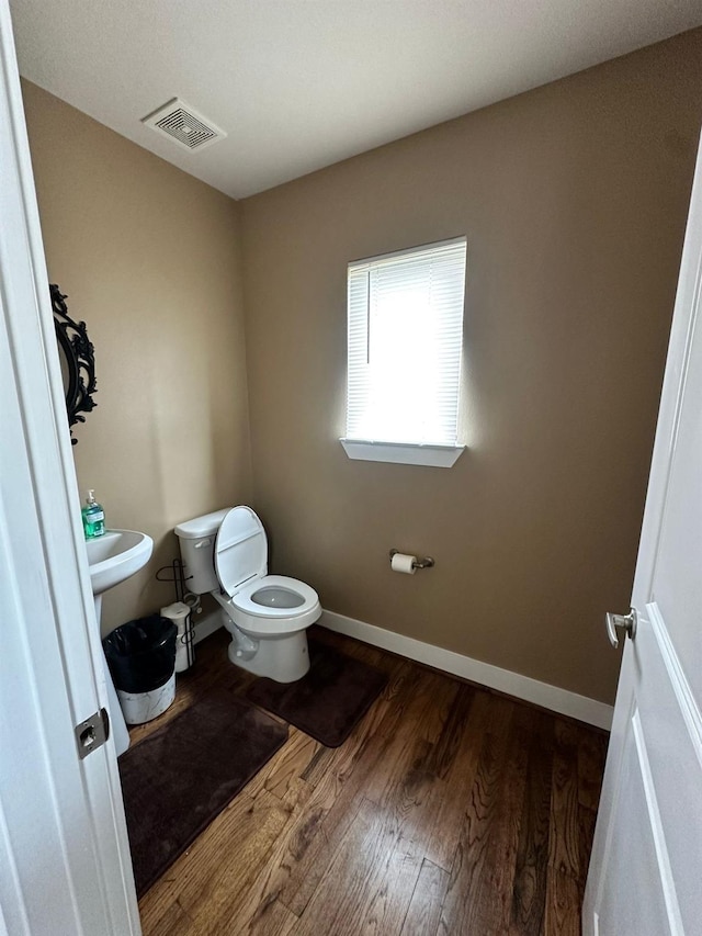 1613 Bonner St, Houston, TX 77007 - half bath featuring wood finished floors, toilet, and baseboards