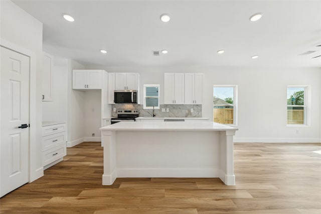 3700 Avenue S, Santa Fe, TX 77510 - kitchen with appliances with stainless steel finishes, white cabinetry, light countertops, decorative backsplash, and a kitchen island