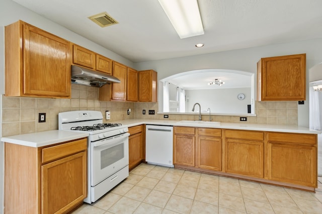 19710 Ringwald Ct, Spring, TX 77379 - kitchen with white appliances, under cabinet range hood, a sink, arched walkways, and decorative backsplash