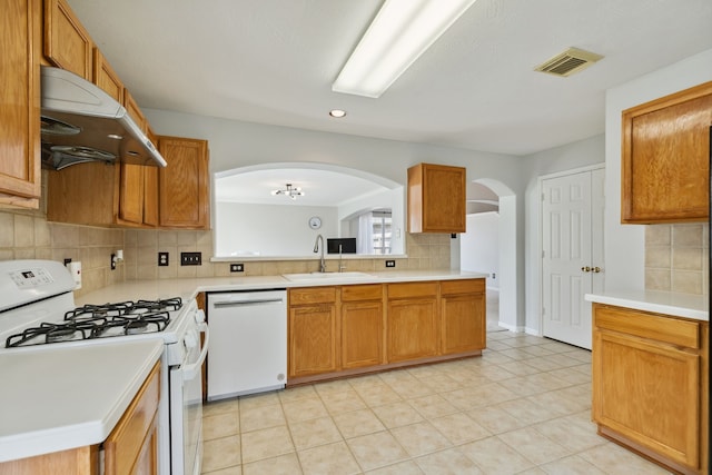 19710 Ringwald Ct, Spring, TX 77379 - kitchen with white appliances, a sink, under cabinet range hood, arched walkways, and tasteful backsplash
