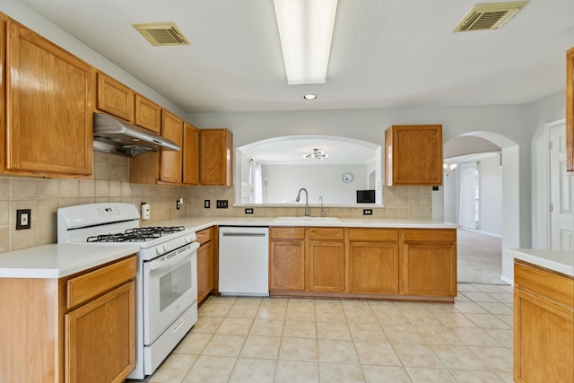 19710 Ringwald Ct, Spring, TX 77379 - kitchen featuring white appliances, under cabinet range hood, a sink, light countertops, and arched walkways
