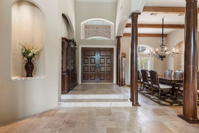 63 N Wooded Brook Cir, The Woodlands, TX 77382 - entrance foyer featuring decorative columns, stone tile flooring, a chandelier, beam ceiling, and arched walkways