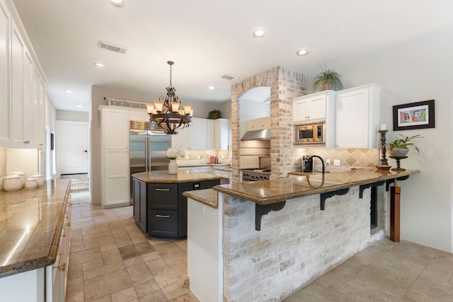 63 N Wooded Brook Cir, The Woodlands, TX 77382 - kitchen featuring built in appliances, decorative backsplash, a peninsula, white cabinetry, and recessed lighting