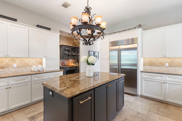 63 N Wooded Brook Cir, The Woodlands, TX 77382 - kitchen featuring built in fridge, white cabinets, decorative backsplash, a kitchen island, and a chandelier