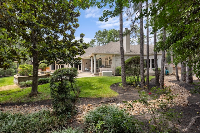 63 N Wooded Brook Cir, The Woodlands, TX 77382 - rear view of property featuring brick siding, a yard, a shingled roof, and a patio