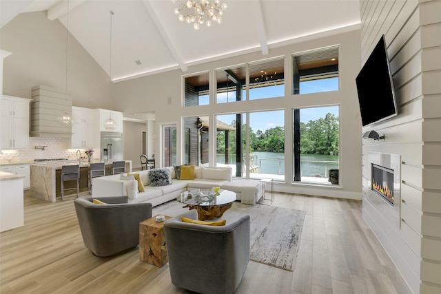 18 N Smith Loop N, Cleveland, TX 77327 - living room featuring high vaulted ceiling, a chandelier, a glass covered fireplace, light wood-style floors, and beam ceiling