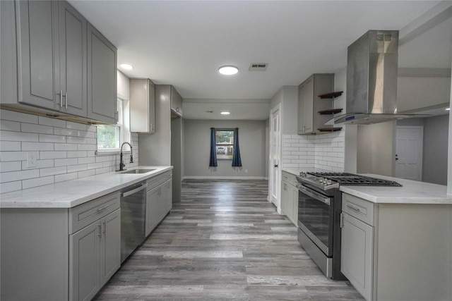 5915 Valkeith Dr, Houston, TX 77096 - kitchen featuring appliances with stainless steel finishes, gray cabinets, island exhaust hood, a sink, and baseboards