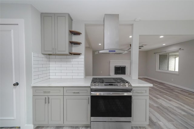 5915 Valkeith Dr, Houston, TX 77096 - kitchen with stainless steel gas stove, island exhaust hood, gray cabinets, open shelves, and decorative backsplash