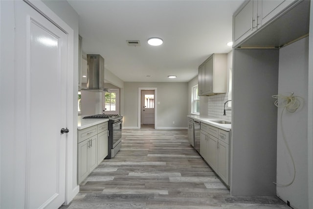 5915 Valkeith Dr, Houston, TX 77096 - kitchen featuring appliances with stainless steel finishes, a sink, exhaust hood, light wood finished floors, and baseboards