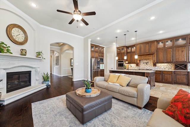 34132 Willow Bluff Ln, Pinehurst, TX 77362 - living room featuring ceiling fan, recessed lighting, arched walkways, baseboards, and light wood-style floors
