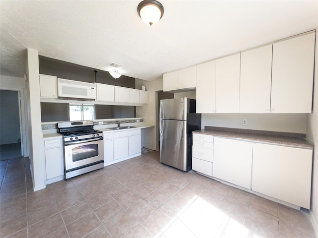 2907 Helmsley Dr, Pearland, TX 77584 - kitchen with appliances with stainless steel finishes, light tile patterned floors, white cabinets, and a sink