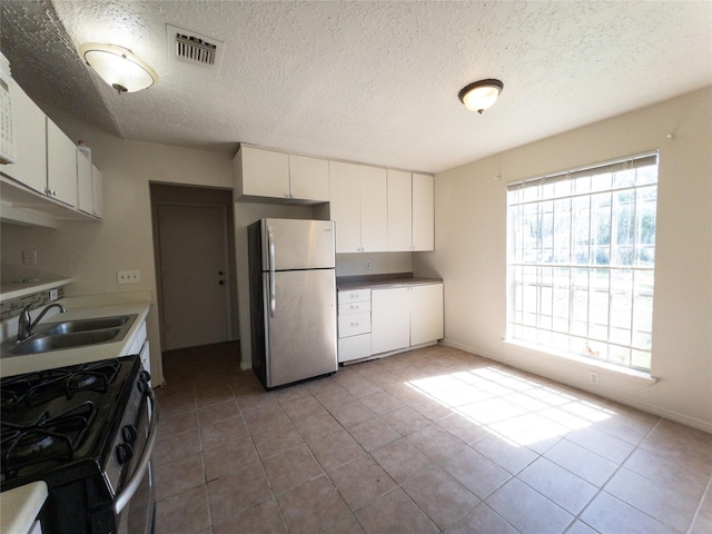 2907 Helmsley Dr, Pearland, TX 77584 - kitchen featuring stainless steel appliances, a sink, a textured ceiling, tile patterned flooring, and white cabinets