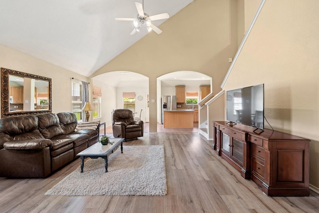 9226 Birch Springs Dr, Houston, TX 77095 - living room featuring arched walkways, ceiling fan, light wood finished floors, high vaulted ceiling, and stairway