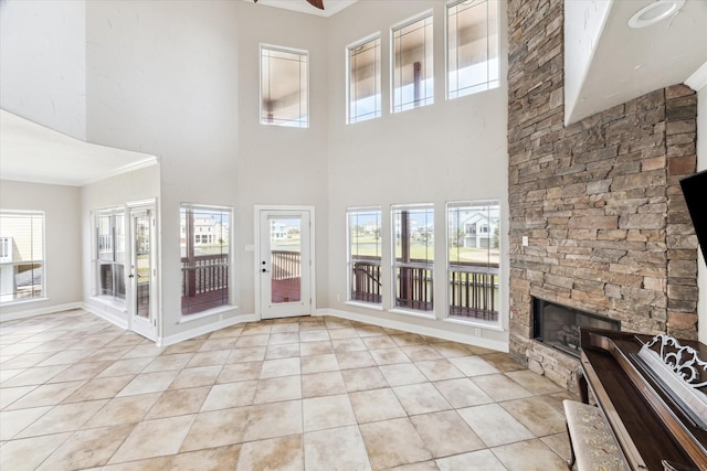 21 Fleming, Hitchcock, TX 77563 - unfurnished living room with light tile patterned floors, a fireplace, a towering ceiling, a ceiling fan, and baseboards