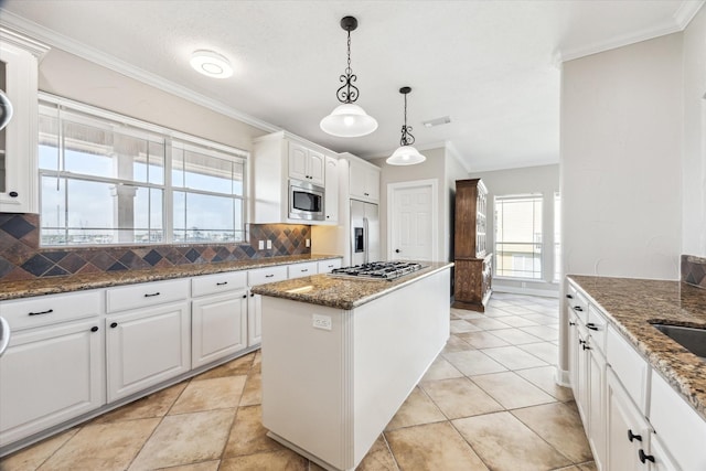 21 Fleming, Hitchcock, TX 77563 - kitchen featuring stainless steel appliances, tasteful backsplash, a kitchen island, white cabinetry, and crown molding
