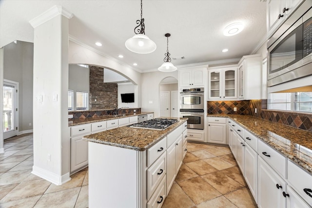 21 Fleming, Hitchcock, TX 77563 - kitchen featuring stainless steel appliances, a kitchen island, ornamental molding, tasteful backsplash, and glass insert cabinets