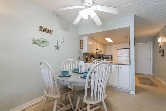 7310 Seawall Blvd Unit 907, Galveston, TX 77551 - dining room featuring baseboards, a ceiling fan, light wood finished floors, and a textured ceiling