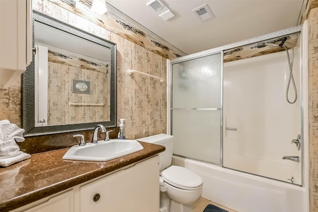 7310 Seawall Blvd Unit 907, Galveston, TX 77551 - bathroom featuring vanity, toilet, bath / shower combo with glass door, and wooden walls