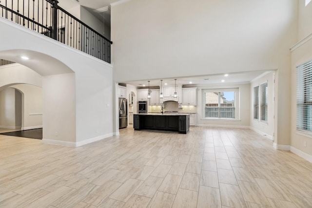15411 Patten Forest Dr, Cypress, TX 77429 - unfurnished living room with a high ceiling, baseboards, arched walkways, crown molding, and light wood-type flooring