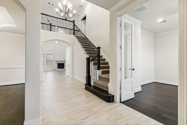 15411 Patten Forest Dr, Cypress, TX 77429 - entrance foyer with stairs, a chandelier, a fireplace with raised hearth, crown molding, and arched walkways