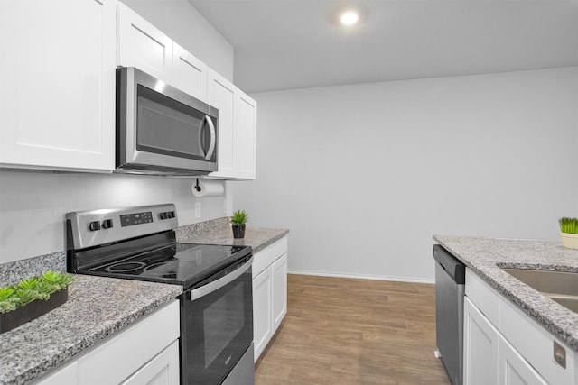 127 Barton Creek Dr, Huntsville, TX 77340 - kitchen with appliances with stainless steel finishes, white cabinetry, light wood-style flooring, baseboards, and light stone countertops