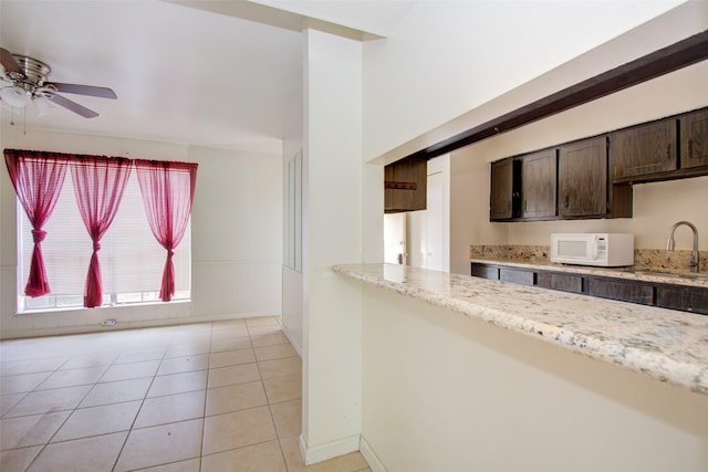 4124 Belle Park Dr, Houston, TX 77072 - kitchen with white microwave, a sink, a ceiling fan, dark brown cabinets, and light stone countertops