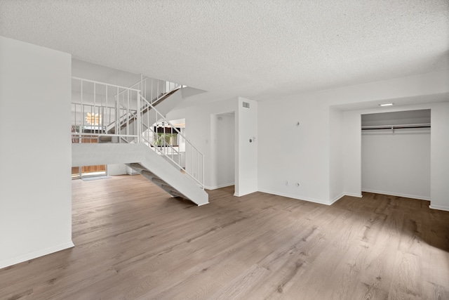 10320 Hammerly Blvd Unit 171, Houston, TX 77043 - unfurnished living room featuring stairs, a textured ceiling, wood finished floors, and baseboards