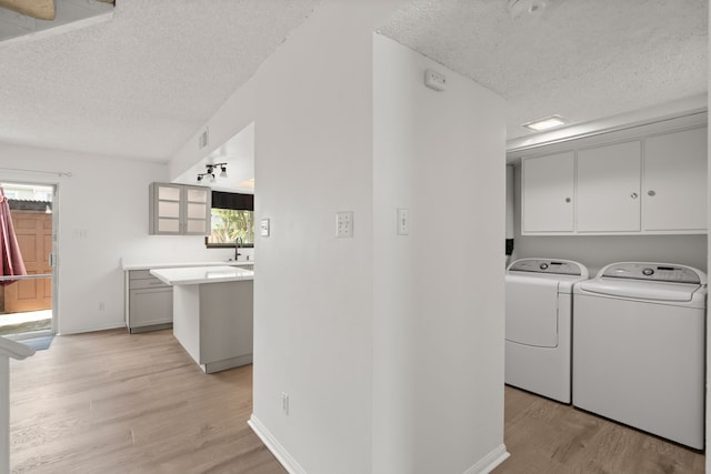 10320 Hammerly Blvd Unit 171, Houston, TX 77043 - laundry room with independent washer and dryer, a textured ceiling, cabinet space, light wood-style floors, and baseboards