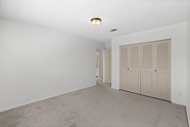 10320 Hammerly Blvd Unit 171, Houston, TX 77043 - unfurnished bedroom featuring carpet flooring, a closet, baseboards, and a textured ceiling