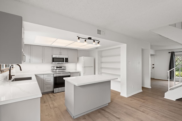 10320 Hammerly Blvd Unit 171, Houston, TX 77043 - kitchen featuring appliances with stainless steel finishes, a sink, light wood-type flooring, a center island, and gray cabinetry