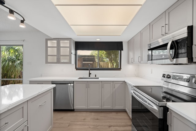 10320 Hammerly Blvd Unit 171, Houston, TX 77043 - kitchen with stainless steel appliances, a sink, light wood-style flooring, gray cabinetry, and light stone countertops