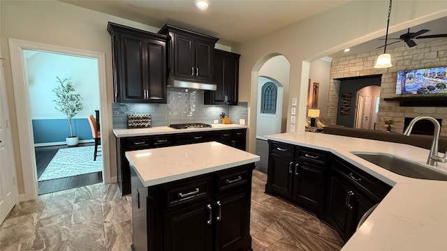 634 Carriage View Ln, Huffman, TX 77336 - kitchen featuring dark cabinets, a sink, under cabinet range hood, arched walkways, and open floor plan