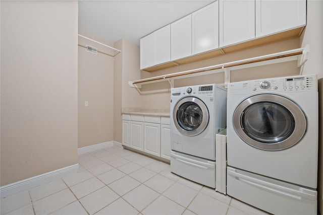 8002 Elm Wood Ct, Baytown, TX 77523 - laundry area featuring washing machine and clothes dryer, cabinet space, light tile patterned floors, and baseboards