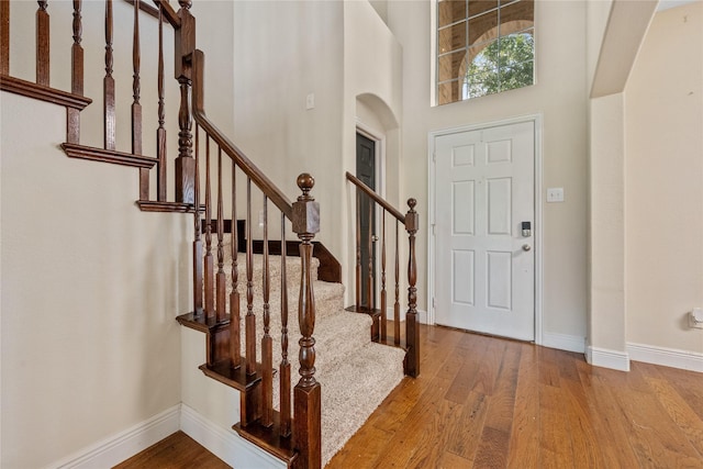 8002 Elm Wood Ct, Baytown, TX 77523 - foyer with wood finished floors, baseboards, arched walkways, stairway, and a high ceiling