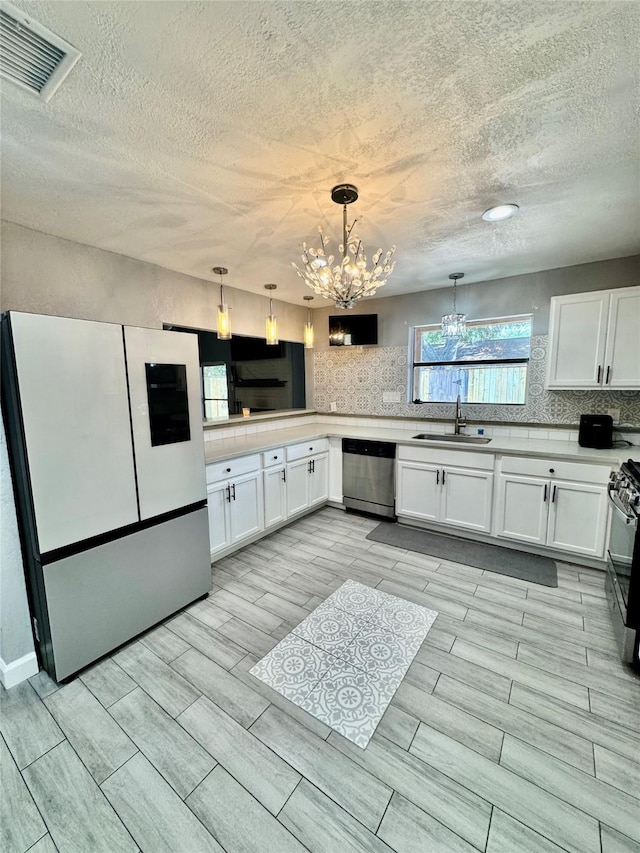 8007 E Oakwood Ct, Houston, TX 77040 - kitchen featuring freestanding refrigerator, dishwasher, a sink, a chandelier, and a textured ceiling