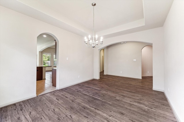 107 N Greenprint Cir, Tomball, TX 77375 - unfurnished room with wood finished floors, a chandelier, arched walkways, and a raised ceiling