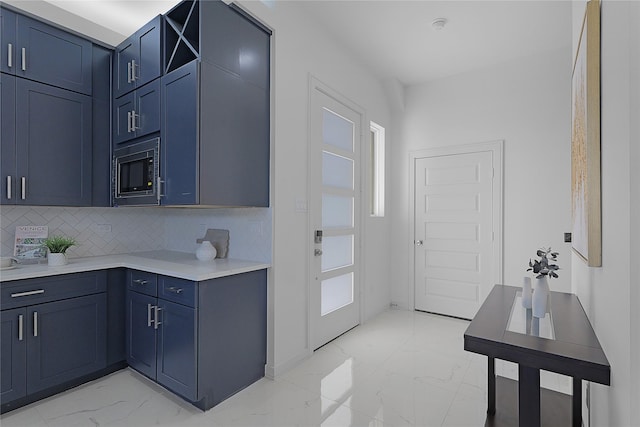 2933 El Fenice Ln, Houston, TX 77057 - kitchen with light marble finish flooring, built in microwave, blue cabinets, decorative backsplash, and light countertops